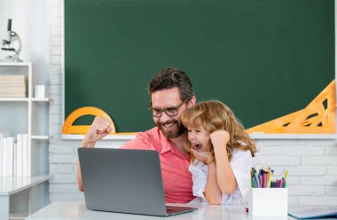Kid boy learning with teacher. Funny little boy study with father in class on blackboard. Child from elementary school