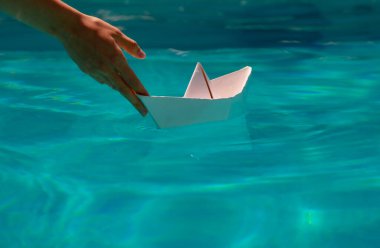 Kağıt gemi yola çıkmaya hazır. Turizm ve seyahat, seyahat hayalleri tatil tatili, yelkenli macerası. El ele tutuşan kağıttan bir tekne.