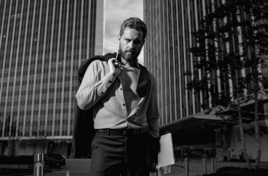 Gömlekli çekici bir adam. Açık havada seksi bir iş adamı. Olgun, güçlü bir iş adamının portresi. İş adamı yürüyor. İş adamı ofisin önünde. Ciddi bir iş adamının iş portresi