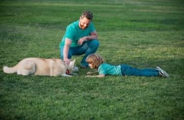 Baba oğul parkta köpekle oynuyorlar. Çocukluk ve ebeveynlik kavramı. Mutlu baba ve oğul dışarıda birlikte oynuyorlar. Hayvan sevgisi