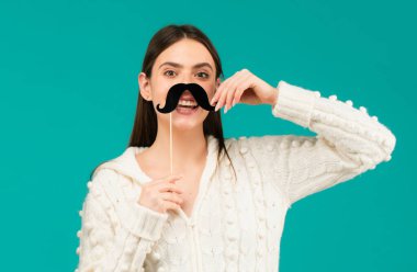 Fotoğraf kabini partisi. Sopadaki sahte bıyık. Mutlu kadın bıyık tutuyor ve gülümsüyor.