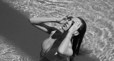 Fashion woman posing by the pool. Summer vacation. Sexy woman with slim sexy body in swimwear bikini relaxing in swimming pool spa. Vacation at luxury resort. Sexy girl in poolside