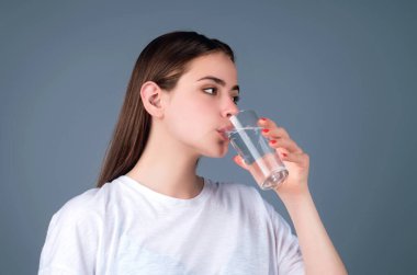 Stüdyonun arka planında izole edilmiş taze bir bardak su içen genç bir kadın. Susamış bir kadın cam içecekler tutuyor susuzluğu, su dengesini, sağlıklı yaşam tarzını engelliyor.