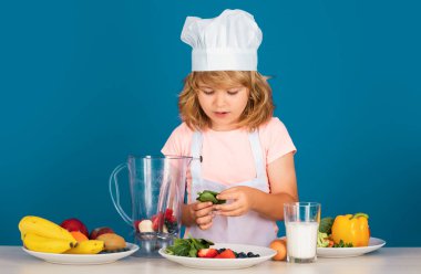 Aşçı şapkalı şefin portresi. Evde yemek pişiren, sebze ve meyvelerden yemek hazırlayan çocuk. Sağlıklı beslenme