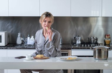 İyi sabahlar. Sarışın, güzel, seksi kız kahvaltısını sağlıklı yiyeceklerle yapıyor. Güzel bir kadının sabahı