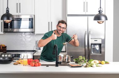 Aşçı mutfakta yemek pişiriyor. Şef aşçı tencereli bir yemek hazırlıyor. Menü tarifi sağlıklı yemek. Şef modern mutfakta yemek pişiriyor. Olgun aşçı mutfakta yemek hazırlıyor.