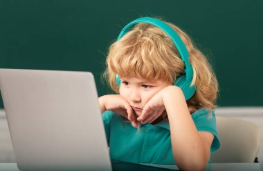 Ciddi öğrenci sınıfta online öğreniyor. Çocuk Zoom ile çevrimiçi video çalışması yapıyor. Öğrenci çocuğu okulda dizüstü bilgisayarla İngilizce öğreniyor.