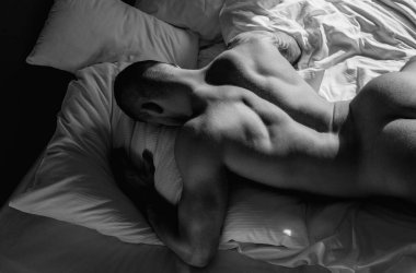 Man lying on bed. Sexy guy in bedroom. Young handsome man in bedroom. Shirtless sexy male model lying on bed in his bedroom. Closeup sexy male round buttocks, Sexy shape butt