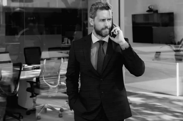 Businessman talking on phone. Businessman in front office. Handsome business man. Business portrait of serious business man outdoor. Middle aged hispanic business man with phone on office building