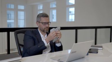 Kolay para, ofiste dolar sayan bir iş adamı. Doları olan takım elbiseli zengin bir adam. Ofis işvereni para banknotlarını tutar. Takım elbiseli adam dolar sayıyor. Para ver, para kazan.