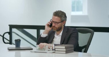 İş adamı telefonda konuşuyor. Ofiste dizüstü bilgisayarla çalışıyor. Ofiste çalışan bir çalışan. İş adamının telefon görüşmesi var. İş adamı telefonda konuşuyor. İş yerinde telefon kullanan bir iş adamı.