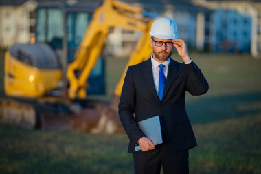 İnşaat işletmecisi ya da şantiye müdürü. İnşaat müdürünün portresi, kazıcının yanında şapka ve takım elbise giymiş. İnşaat yöneticisi veya denetçisi ile yenileme