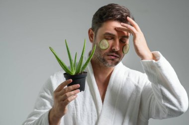 Beauty man hold aloe vera. Aloe Vera 'lı orta yaşlı bir adam stüdyo arka planında izole edilmiş. Kozmetik deri maskesi için Aloe Vera. Yüz maskesi ve aloe vera. Spa, cilt bakımı, sağlık ve yüz bakımı