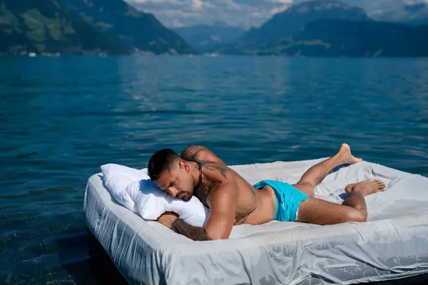 Summer Travel vacation holiday. Relax man, freedom, calm and carefree on summer concept. Muscular man lying on cozy Mattresses, sleep, good dreams concept. Sexy man floating on the Bed with blanket