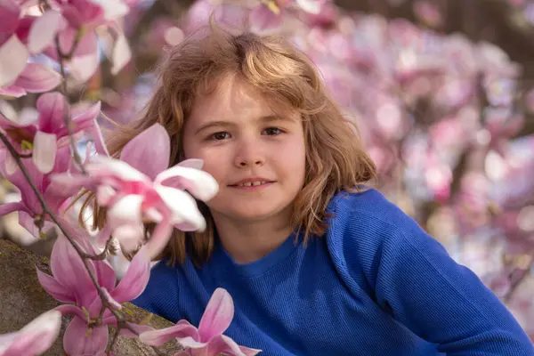 Kid in spring cherry blossom park. Happy childhood. Spring holidays. Adorable boy in spring garden. Cute little kid boy under a blossom flowering tree. Portrait of beautiful kid in spring garden