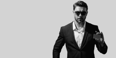 Gri arka planda kredi kartı olan bir adamın stüdyo portresi. Para yönetimi ve kredi puanı. Ödül programları. Kredi limiti. Başlık için afiş, kopyalama alanı. Web tasarımı için poster