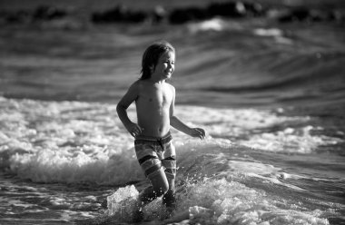 Çocuk deniz dalgalarında zıplıyor. Su birikintilerinden atla. Yaz tatili