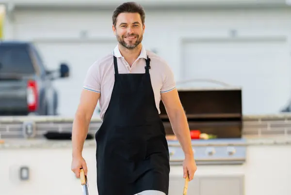 stock image Grill cook. Chef with BBQ cooking tools. Barbecue and grill. Picnic and barbecue party. Chief cook with utensils for barbecue grill. Barbeque on holiday picnic. Man grilling a steak on BBQ