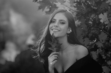 Sonbahar mevsimi. Yaprakları yapraklı genç bir kadının portresi. Sonbaharda güzel bir kız. Sonbaharda sarı yapraklı şehvetli bir kadın. Sonbahar arkaplanında yaprağı olan güzel bir kadın.