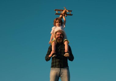 Çocuk babasının omuzlarında oturuyor. Çocuk oğlu pilot ve baba babası uçakla