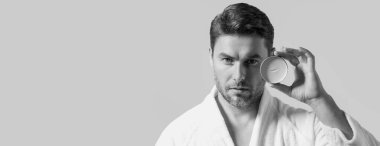 Erkek cilt bakımı için kozmetik kremi reklamı yapan bir adam. Erkek derisi için krem. Erkek derisi. İzole edilmiş stüdyo afişi. Erkekler için organik kozmetik. Doğal insan cilt bakımı için kozmetik tutuyor.