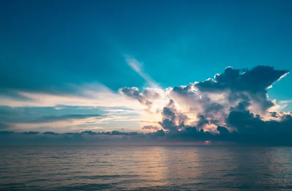 夕阳西下在热带海滩的海面上 有着日出般的云彩 旅行度假的横幅 美丽的天空和水中的反光 海上的暮色 平静的 金色的天空背景 — 图库照片