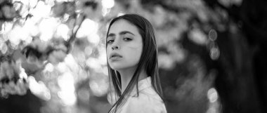 Çiçekli kiraz ağacının arka planında poz veren güzel romantik genç bir kadın. Bahar ve yazın ilham kaynağı. Sancak bahar tasarımı, web sitesi başlığı reklamı. Bahar çiçeği arkaplanı