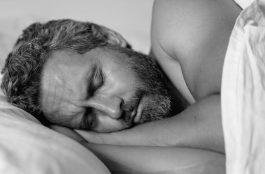 Yatağa git. Yaklaş. Erkek model beyaz yatakta uyuyor. Seksi üstsüz adam yatak odasında uyuyor. Latin kökenli olgun bir adam sabahları evde uyuyor. İyi uykular, uyku vakti. Yatakta uyuyan adam.