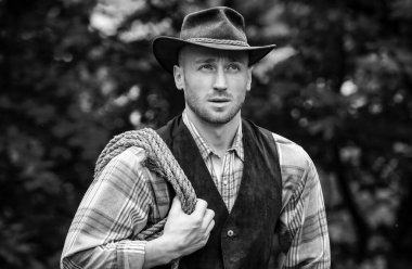 Yeşil arka planda kement ipi olan bir kovboy. Batı hayatı. Yakışıklı sakallı batı çiftçisi. Kovboy ya da çiftçi portresi. Batı