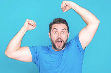 Stüdyo arka planında izole edilmiş milenyum insanının şaşırmış yüzü. Yakışıklı mutlu genç adam, kazanan hareketi gösteriyor. Kolları açık başarılı bir adam. Şok olmuş heyecanlı adam el kaldırsın.