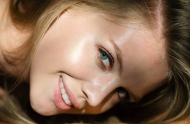 Siyah stüdyoda gölgeli, güzel yüzlü seksi bir kadın. Sarışın, gülümseyen, yakından bakan kız. Şehvetli gülümseme, gülen yüz