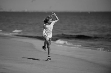 Çocuk deniz kıyısında kumsalda koşuyor. Sportif çocuk doğada koşuyor. Aktif sağlıklı çocuk koşucusu dışarı koşuyor.