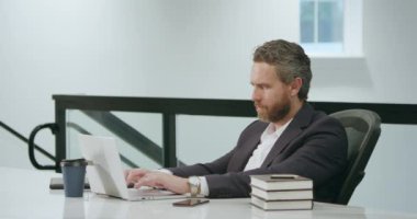Ofisinde dizüstü bilgisayarı olan bir iş adamı. Modern ofiste çalışan uzaktan kumandalı personel. İş adamı çevrimiçi toplantıda. İnternette çalışan İspanyol iş adamı. İş yerinde laptop kullanan olgun bir iş adamı