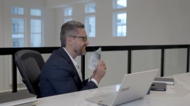 Ofiste parası olan heyecanlı bir iş adamı. Paralı takım elbiseli zengin bir adam. Başarılı bir iş adamı dolar banknotlarını elinde tutar. Takım elbiseli zengin yönetici para sayıyor. Bütçe, ödeme faturaları, mali planlama