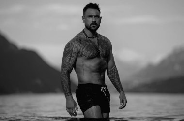 Kaslı adam gölde suda rahatlıyor. Suyun içindeki çekici erkek seksi model. Yakışıklı çocuk Alps gölü suyunda dinleniyor. Suyun içinde çıplak, seksi bir adam. İnsan özgürlüğü yaşam tarzı. Güçlü kaslı adam.