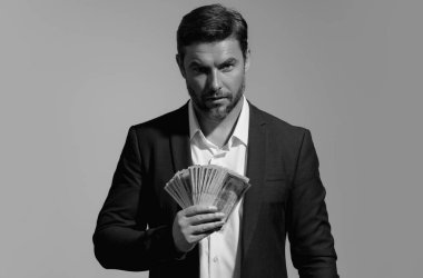 Başarılı bir iş adamı para sayıyor. Yakışıklı orta yaşlı adam 100 dolarlık banknotları tutuyor. Elinde para tutan adam. Kâr ve finansal başarı. Dolar nakiti olan zengin bir adam.