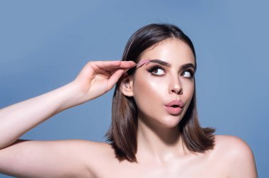 Eyebrow shaping, woman combs eyebrows with a brus. Eyebrow line. Makeup and cosmetology concept. Female model with long eyelashes and thick eyebrows. Perfect shaped brow