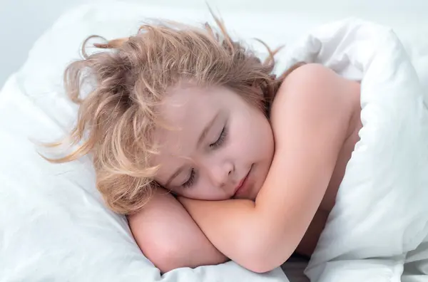 Morning sleep. Lovely face of blonde caucasian child, sleeping on bed. Sweet dreams. Little baby boy sleeping while lying on bed at home