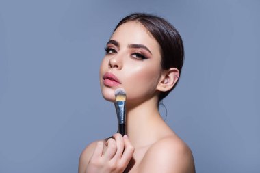 Woman applying foundation powder or blush with makeup brush. Facial treatment, perfect skin, natural make up, facial beauty. Isolated on studio background. Applying makeup