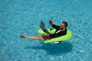 Boş bir hafta sonu ve uzak bir serbest çalışma. Çılgın çizgi roman işi. Yüzme havuzunda dizüstü bilgisayarı olan takım elbiseli komik bir iş adamı. Uzak bir yaz çalışması. İş adamı takım elbiseyle havuzda dinleniyor.