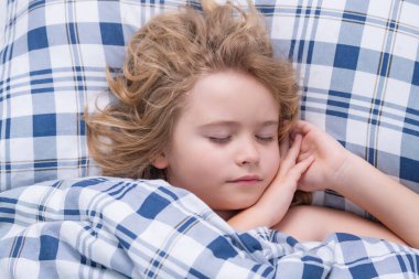 Sessiz bir uyku. Çocuk yatakta uyuyor. Çocuk battaniyenin altında uyuyor, yastığın üzerinde yatıyor. Çocuk uyuyor, sağlıklı bir uyku çekiyor ya da kestiriyor.