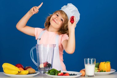 Aşçı şapkalı şefin portresi. Evde yemek pişiren, sebze ve meyveli ahududu püresi hazırlayan çocuk. Sağlıklı beslenme