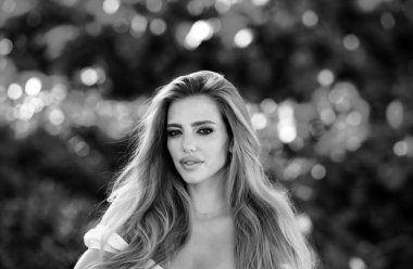 Güzel genç kız bahar parkında dinleniyor. Mükemmel ciltli, makyajlı ve uzun sarı saçlı çekici bir kadın.