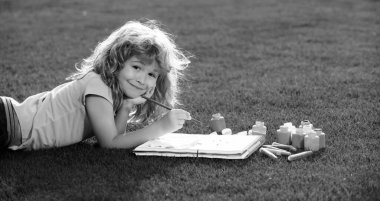 Çocuk çizimi. Okul çocukları yaz parkında resim çiziyor, resim yapıyor. Küçük ressam açık havada resimler çizer.