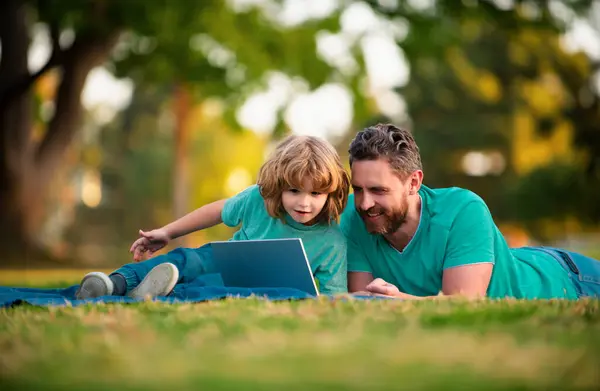 Father and son with a laptop on nature in park