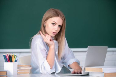 Sınıfta okuyan genç bir üniversite öğrencisinin portresi. Tahta altyapısı var. Güzel beyaz kız öğrenci üniversitede uzaktan öğrenim görüyor.