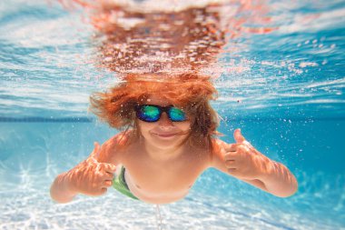 Çocuk yüzme havuzunda suya dalıyor. Küçük çocuk havuzda su altında yüzüyor. Çocuk su altında ya da havuzda yüzüyor. Yaz tatili eğlencesi. Yüzme havuzundaki su altı portresi