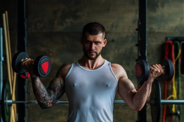 Halterle egzersiz yapan bir adam. Formda bir model ağırlık kaldırıyor, spor salonunda egzersiz yapıyor. Halterle antrenman. Güçlü, kaslı, formda, halterli ve ağır ağırlıklı bir adam. Kas pazıları için alıştırmalar