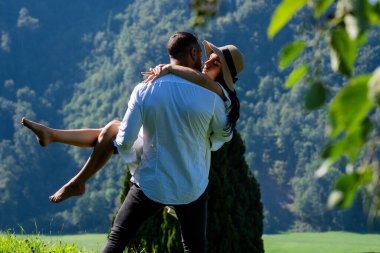 Seksi çift tutkuyla doğayı kucakladı. Romantik bir öpücük. Doğayı öpen çiftler. Öpüşen çiftler. Aşık çift, güneşin öptüğü çayırda öpüştü.