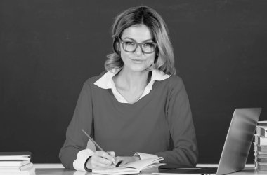 Üniversite sınıfında dizüstü bilgisayarı olan genç bir kız öğrenci. Öğrenci üniformalı kız öğrenci. Sınıfta ders çalışmak. Tahtada üniversite öğrencisi. Masadaki kız öğrenci. Öğrenci günü. Okula geri dön.